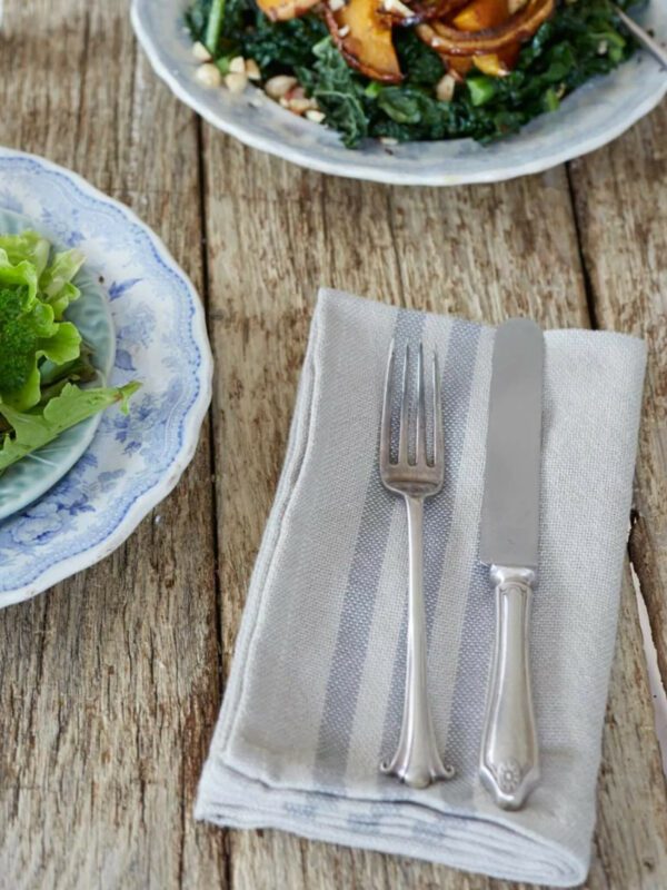 Servetten linnenlook met grijze strepen op een gedekte tafel me bestek en borden met salades