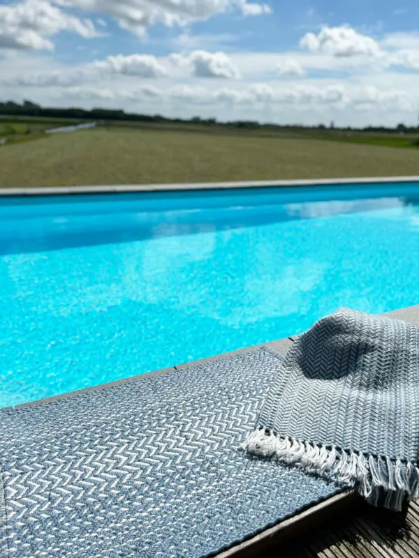 Luchtblauwe badmat en luchtblauwe deken bij zwembad