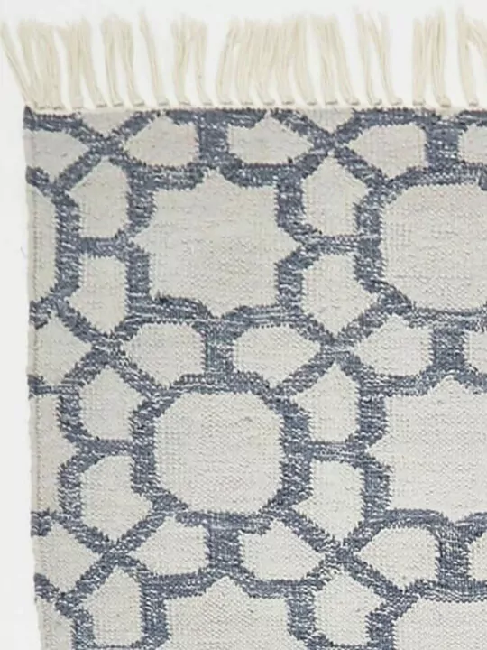 Detailfoto van hoek van vloerkleed grijs met blauw en franjes