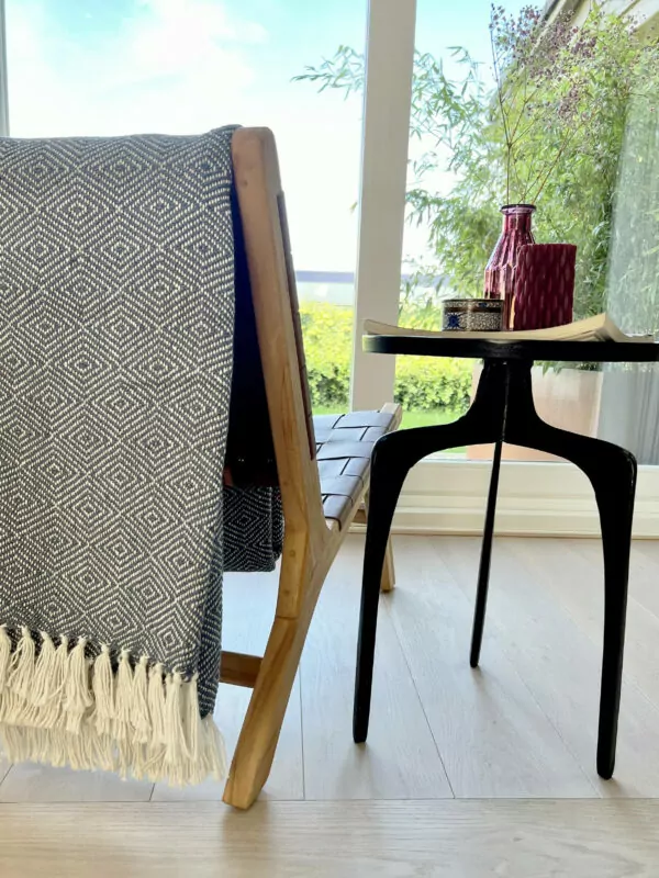 Marine blauwe deken met witte franjes gedrapeerd over bruine leren stoel