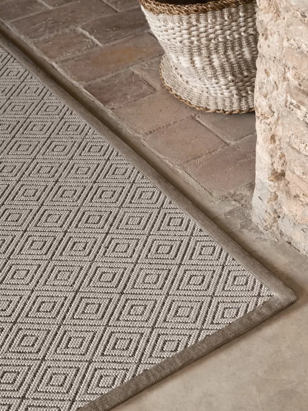 Fijn geweven buiten vloerkleed met diamant patroon met beige en bruine accenten bij muur
